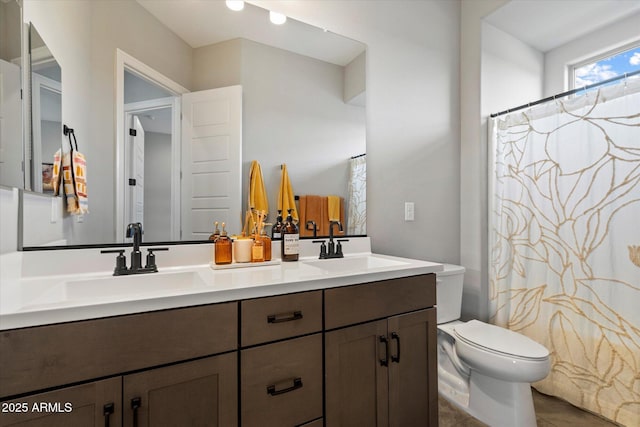bathroom featuring a sink, toilet, double vanity, and a shower with shower curtain