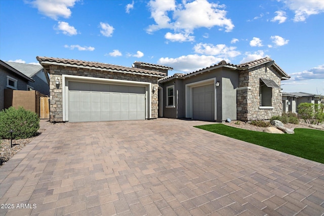 view of front of home featuring stone siding, a garage, a tile roof, stucco siding, and decorative driveway
