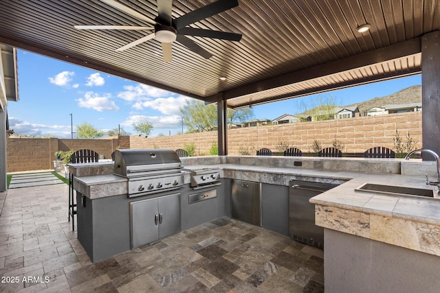 view of patio featuring an outdoor kitchen, grilling area, a fenced backyard, and a sink