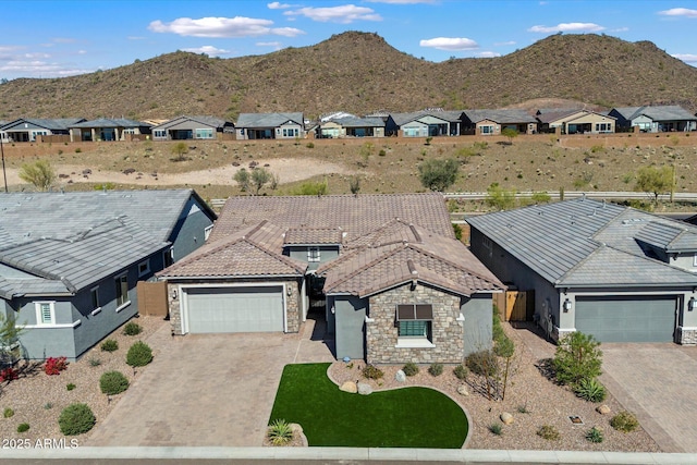 view of front facade with a mountain view, driveway, stone siding, and a garage
