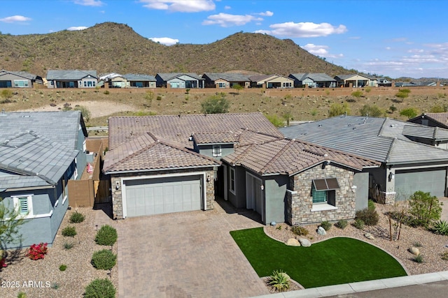 view of front of house featuring a residential view, driveway, stone siding, a garage, and a tiled roof