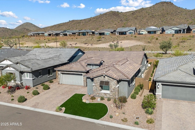 exterior space featuring stucco siding, stone siding, an attached garage, a mountain view, and driveway