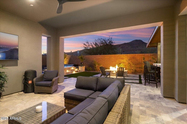 patio terrace at dusk featuring an outdoor living space with a fire pit and a fenced backyard