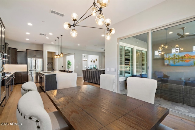 dining space with light wood-style floors, recessed lighting, a notable chandelier, and visible vents