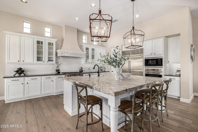 6328 W Fetlock Trl, Phoenix, AZ 85083 - kitchen with white cabinets, light wood-style flooring, premium range hood, and built in appliances