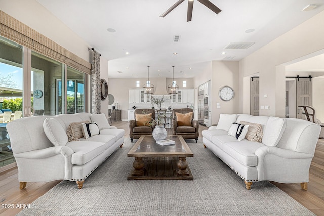 6328 W Fetlock Trl, Phoenix, AZ 85083 - living area with a barn door, wood finished floors, visible vents, and ceiling fan