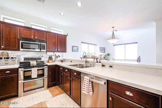 kitchen with decorative light fixtures, stainless steel appliances, light tile patterned floors, and sink