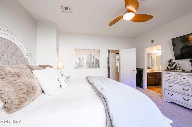 bedroom with ensuite bathroom, ceiling fan, and light carpet