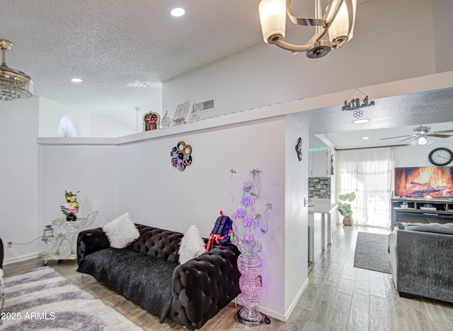 living room featuring a textured ceiling and ceiling fan with notable chandelier