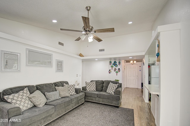 living room featuring ceiling fan, wood-type flooring, high vaulted ceiling, and a textured ceiling