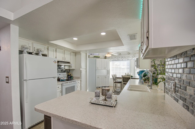 kitchen featuring ceiling fan, a tray ceiling, white appliances, white cabinets, and sink