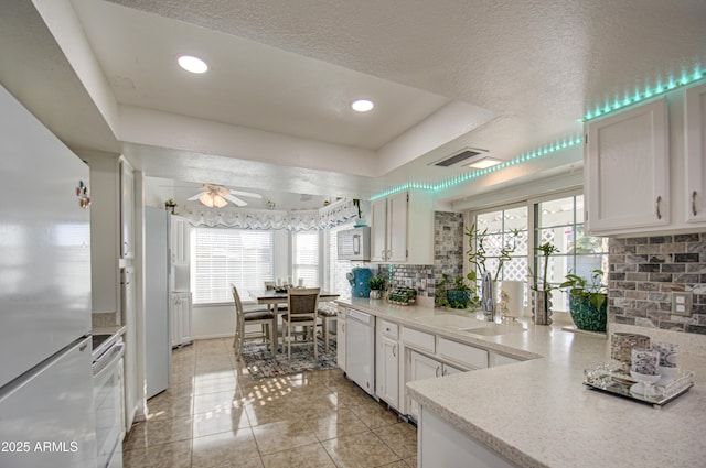 kitchen with tasteful backsplash, sink, white appliances, and white cabinetry