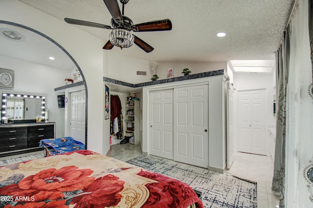 bedroom featuring ceiling fan, lofted ceiling with skylight, and a textured ceiling