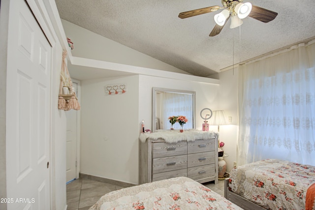 tiled bedroom featuring a textured ceiling, ceiling fan, lofted ceiling, and a closet