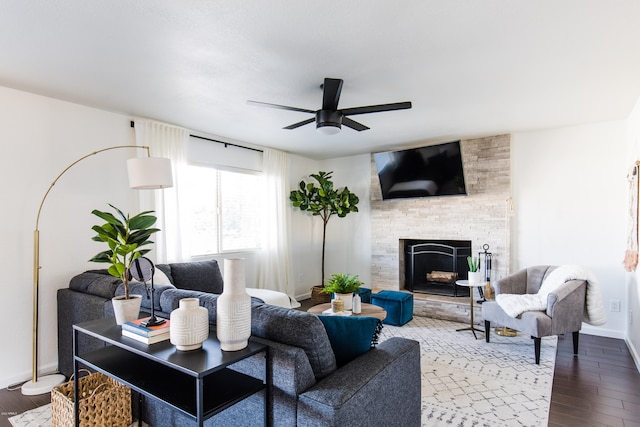 living room with dark wood-style floors, a fireplace, baseboards, and a ceiling fan