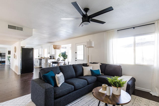 living room with a ceiling fan, wood finished floors, visible vents, and a textured ceiling