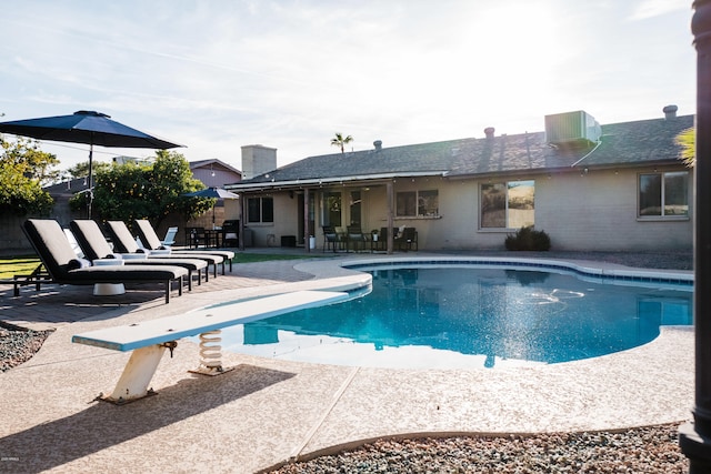 view of pool with a patio, fence, a diving board, a fenced in pool, and central AC unit