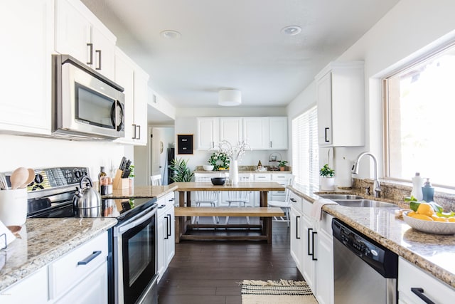 kitchen with a sink, appliances with stainless steel finishes, white cabinets, and dark wood finished floors