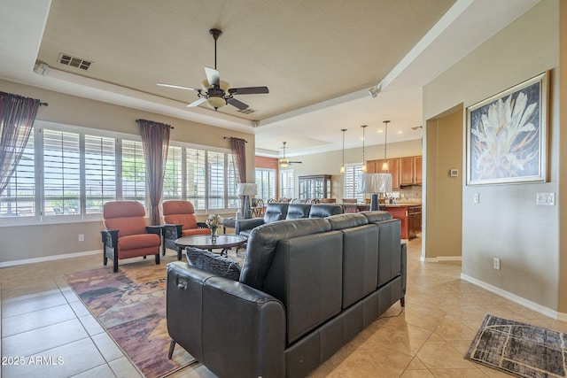 4497 E Ficus Way, Gilbert, AZ 85298 - living area with visible vents, light tile patterned flooring, baseboards, ceiling fan, and a tray ceiling
