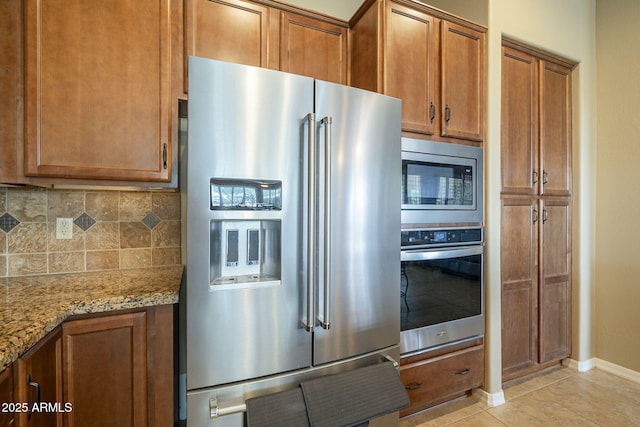4497 E Ficus Way, Gilbert, AZ 85298 - kitchen featuring brown cabinetry, tasteful backsplash, light stone countertops, baseboards, and stainless steel appliances