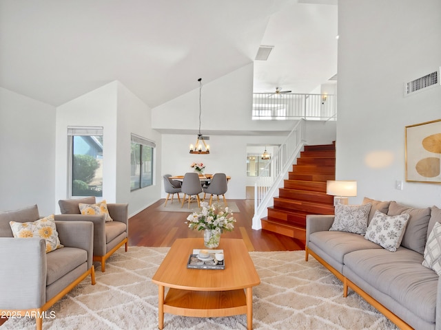 living room with a notable chandelier, wood-type flooring, and high vaulted ceiling