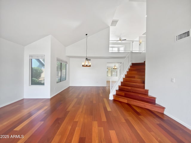 interior space featuring hardwood / wood-style floors, ceiling fan with notable chandelier, and high vaulted ceiling