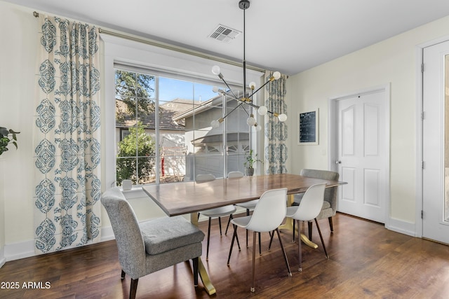 dining area featuring visible vents, a notable chandelier, baseboards, and wood finished floors