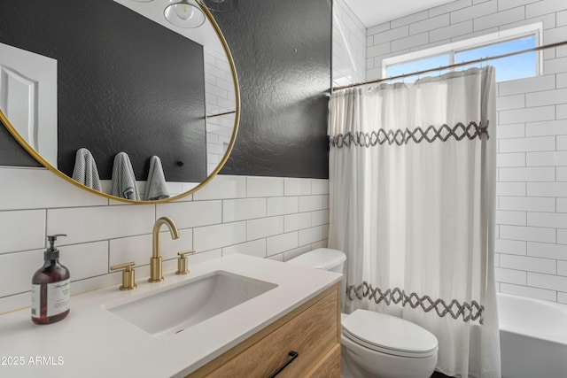 full bathroom featuring a textured wall, toilet, shower / tub combo, vanity, and tile walls