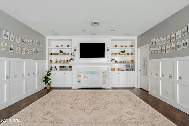 unfurnished living room with built in shelves, dark wood-type flooring, and visible vents