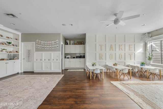 interior space featuring ceiling fan, visible vents, white cabinets, built in features, and dark wood-style floors