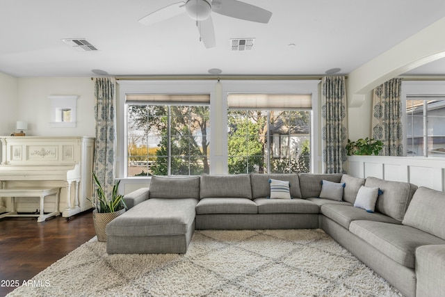 living room with a wealth of natural light, dark wood-style flooring, and visible vents