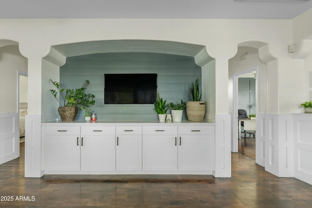 living room featuring dark wood-style floors, a wainscoted wall, and a decorative wall