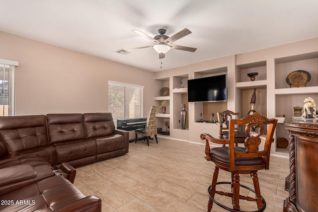 living room with built in shelves and ceiling fan