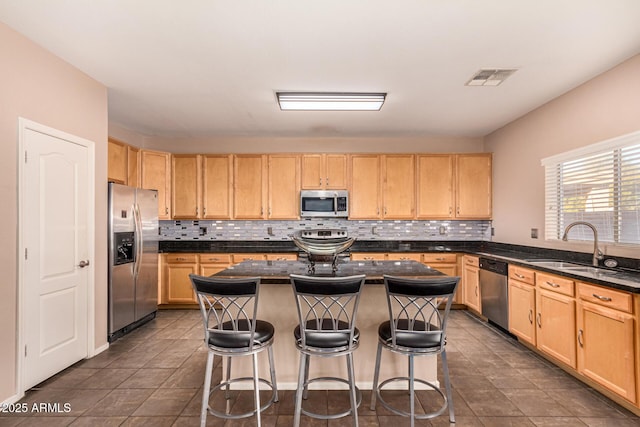 kitchen featuring sink, a breakfast bar area, appliances with stainless steel finishes, a center island, and light brown cabinets