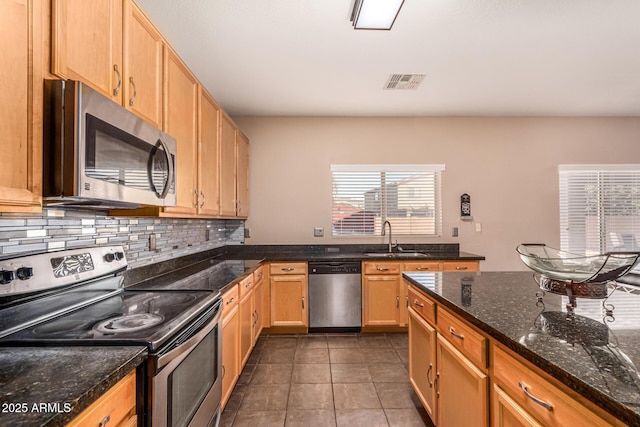 kitchen featuring sink, dark stone countertops, backsplash, dark tile patterned floors, and stainless steel appliances