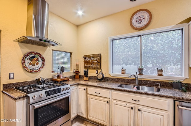 kitchen with dark stone countertops, wall chimney exhaust hood, appliances with stainless steel finishes, and a sink