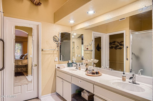 full bath with a sink, a shower stall, ensuite bath, and double vanity