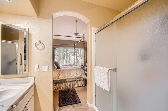 bathroom with a textured wall, ensuite bathroom, a ceiling fan, a stall shower, and vanity