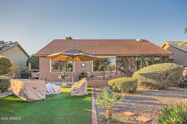 view of front facade with a front yard, a tile roof, and stucco siding