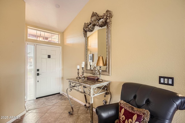 foyer entrance featuring lofted ceiling, light tile patterned flooring, and baseboards