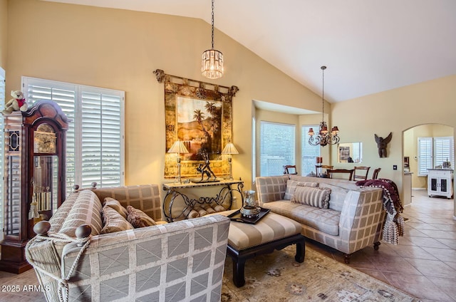 living area with arched walkways, high vaulted ceiling, tile patterned floors, and a notable chandelier