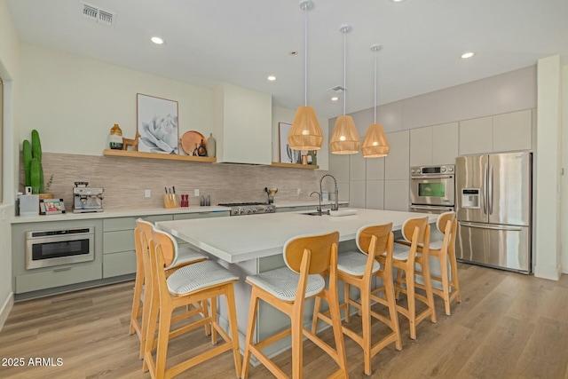 kitchen with appliances with stainless steel finishes, backsplash, open shelves, light countertops, and light wood-style floors