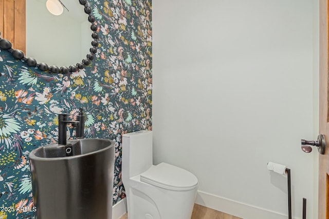 bathroom featuring toilet, baseboards, and wood finished floors
