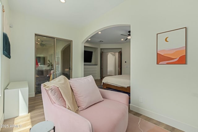 living area with a ceiling fan, light wood-style flooring, arched walkways, baseboards, and recessed lighting