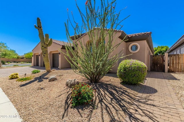 view of front of home with stucco siding, a tiled roof, a gate, and an attached garage