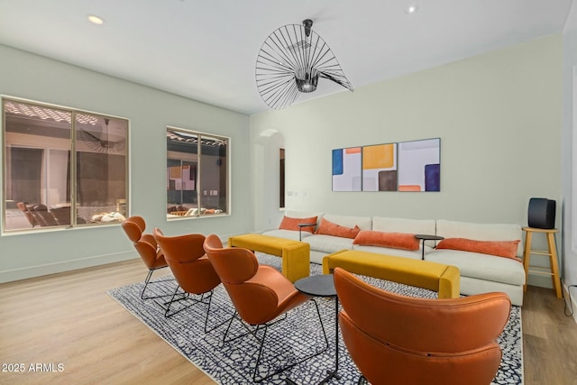 living area with arched walkways, wood finished floors, baseboards, and recessed lighting