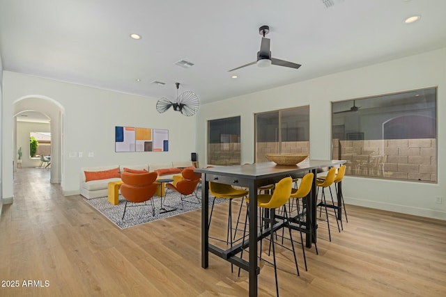 dining area with arched walkways, light wood-style flooring, ceiling fan, baseboards, and recessed lighting
