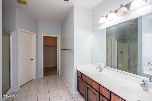 bathroom featuring tile patterned floors, a shower with shower door, and vanity