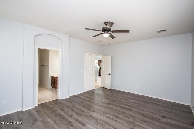 unfurnished bedroom with ceiling fan, hardwood / wood-style floors, and connected bathroom