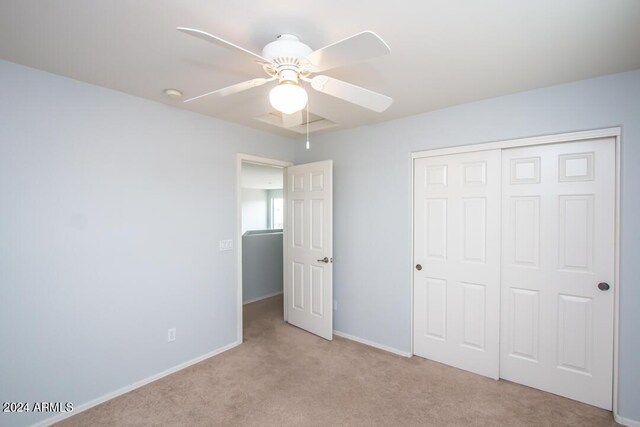 unfurnished bedroom featuring ceiling fan, light colored carpet, and a closet